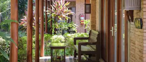 A covered outdoor area with a bench, a small table, and a potted plant.