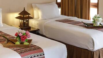 Ein Hotelzimmer mit zwei Betten, einem Nachttisch mit einer Laterne und einem dekorativen Tablett mit Blumen.