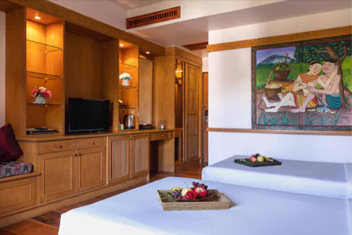 A room with a wooden cabinet, a flat-screen TV, a white sofa, and a painting on the wall.