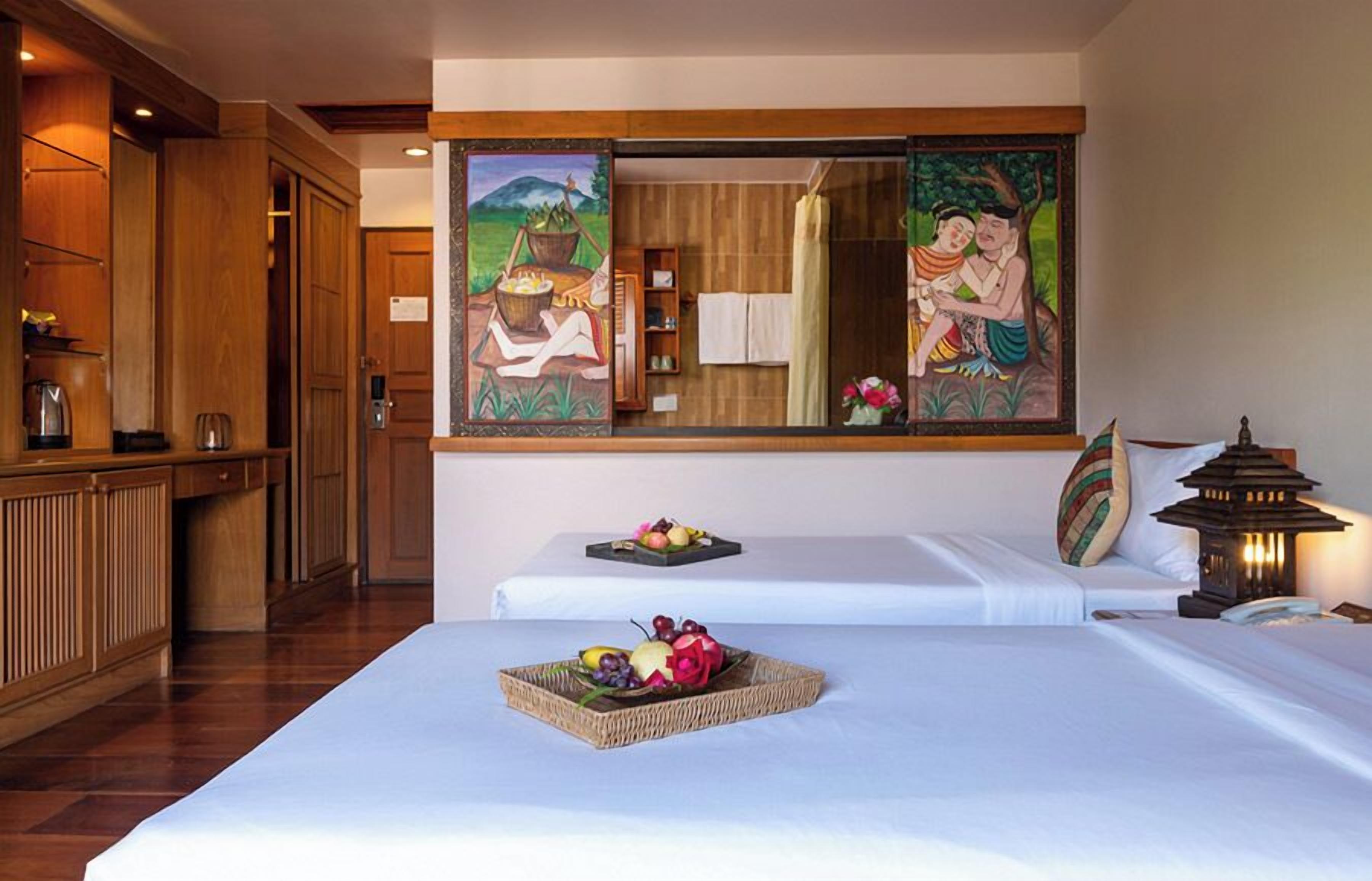 Habitación de hotel con dos camas, un armario de madera, un cuadro y un farol.