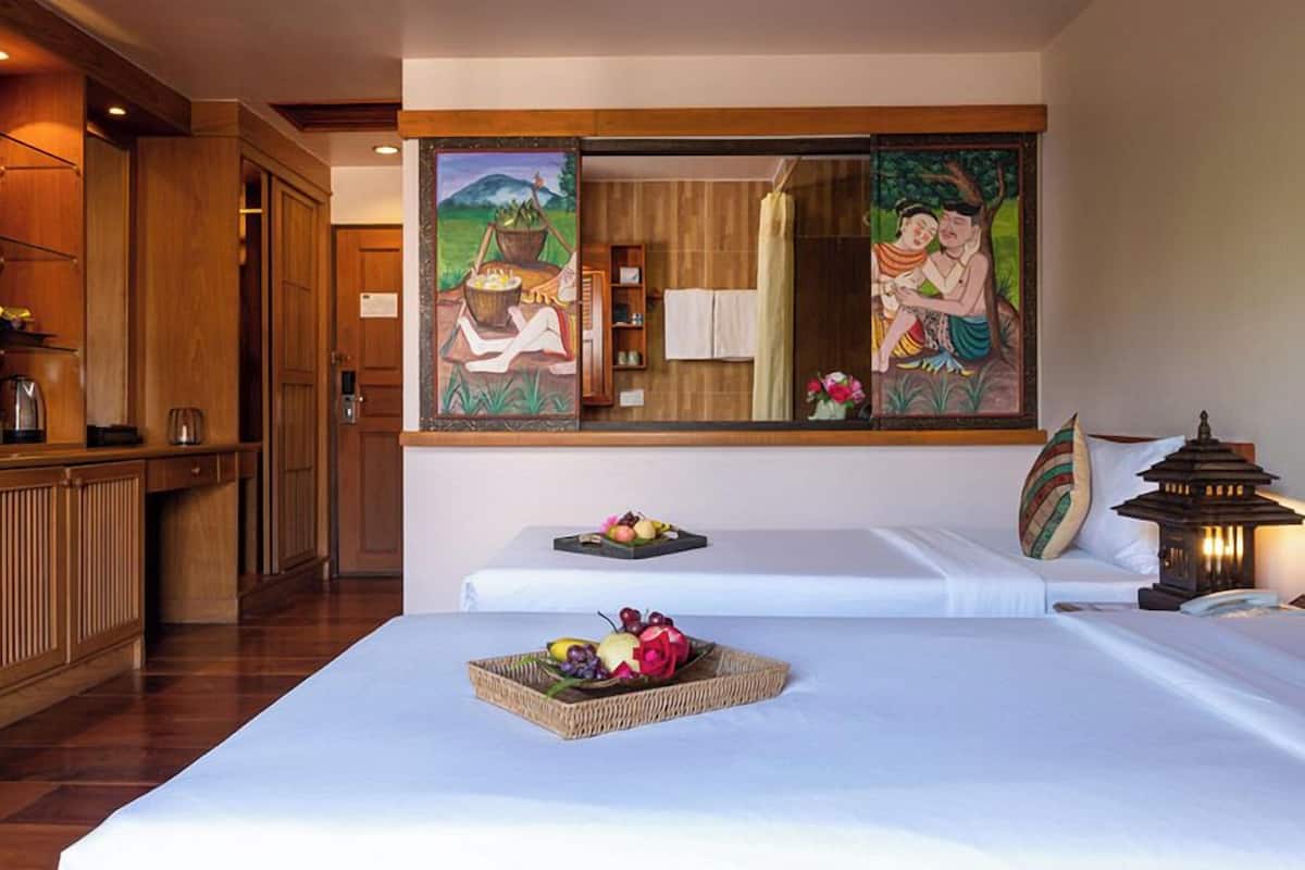 Habitación de hotel con dos camas, un armario de madera, un cuadro y un farol.