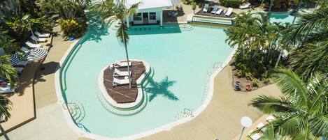 Un complejo turístico con piscina central, zonas de descanso y un pequeño embarcadero.