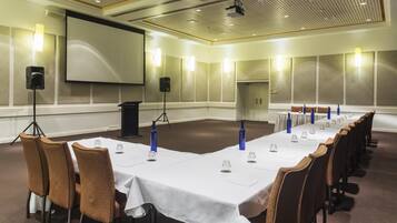 A conference room with a long table, chairs, a projector screen, and a whiteboard.