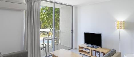 Una sala de estar moderna con un televisor de pantalla plana, una mesa de centro de madera y un sofá.