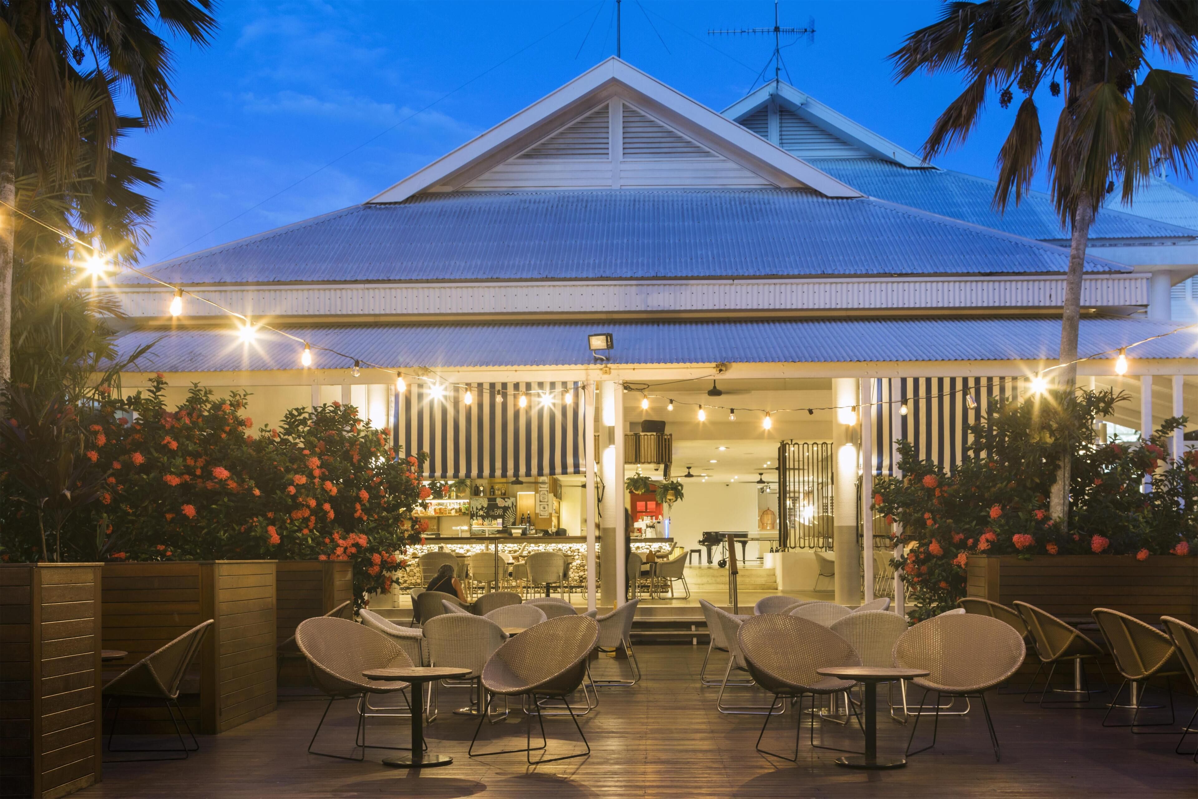 A restaurant with outdoor seating, a bar, and a view of the building's roof.