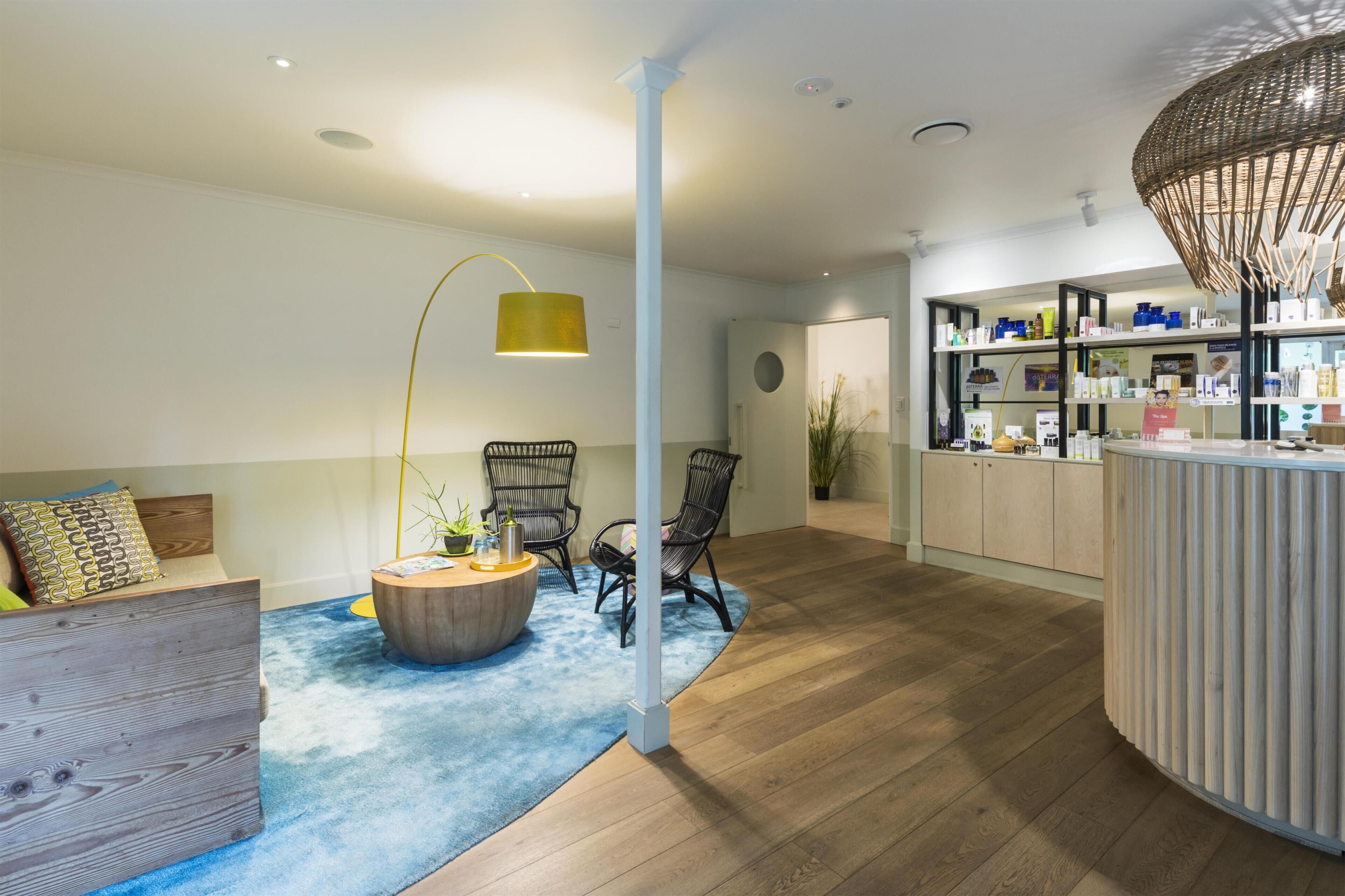 Un interior modern amb un terra de fusta, una taula de cafè rodona, un sofà i una taquilla de recepció amb prestatges.