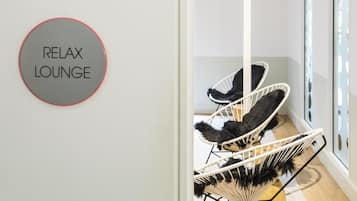 A room with a sign reading 'RELAX LOUNGE' and three black and white chairs.