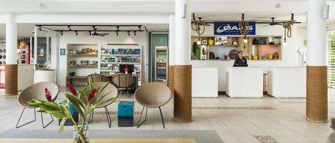 A hotel lobby with a reception desk, seating area, and a variety of amenities including a minibar and a display of toiletries.
