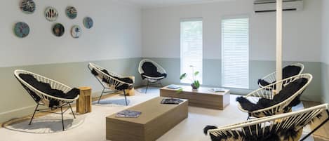 Una habitación moderna con sillas de mimbre blanco y negro, una mesa de centro de madera y decoración en la pared.