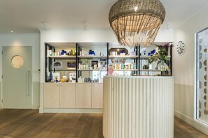 A modern reception area with a central counter, wooden flooring, and a decorative hanging light fixture.