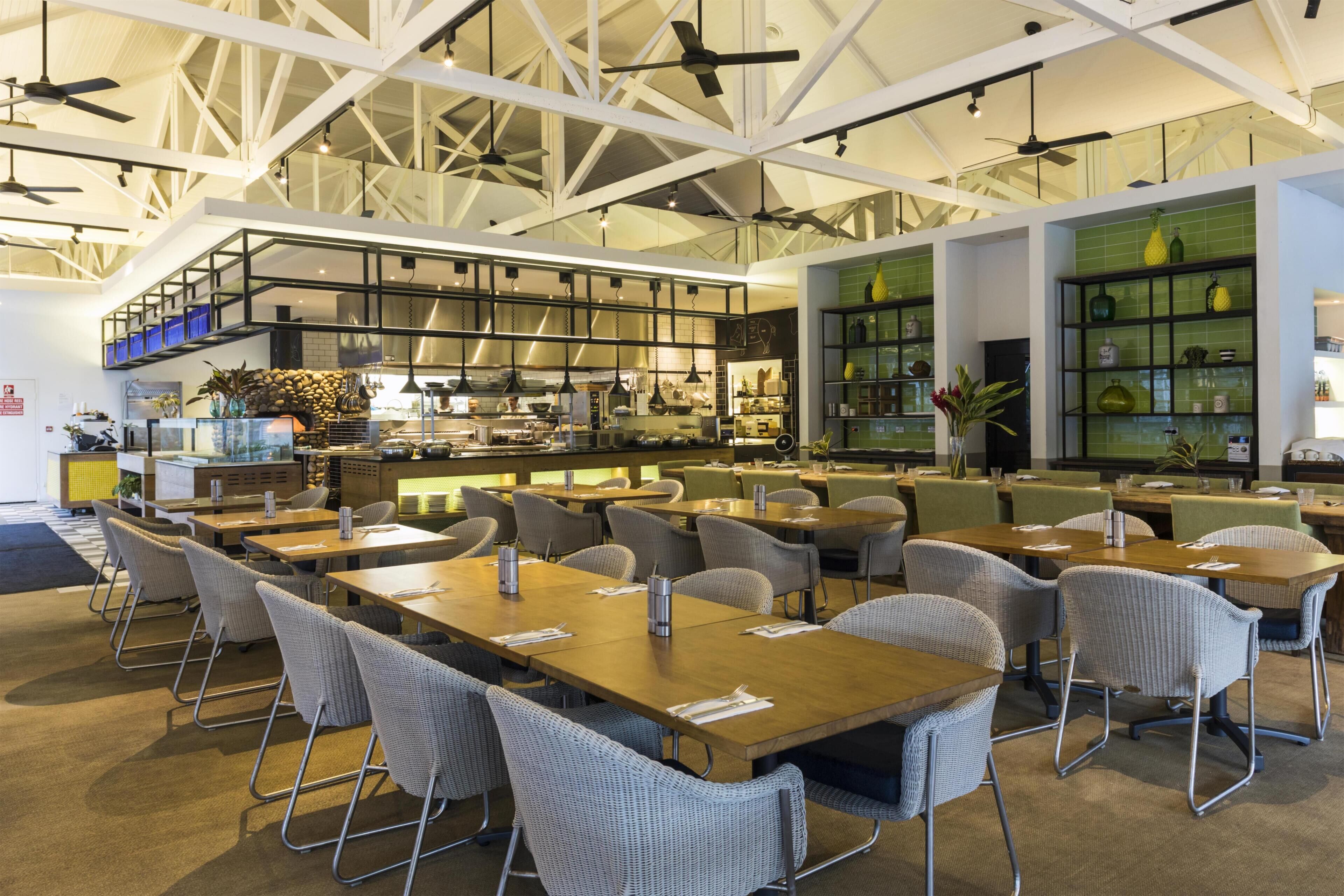 Un restaurant spacieux avec de hauts plafonds, des poutres apparentes et différents types de mobilier, notamment des tables et des chaises.