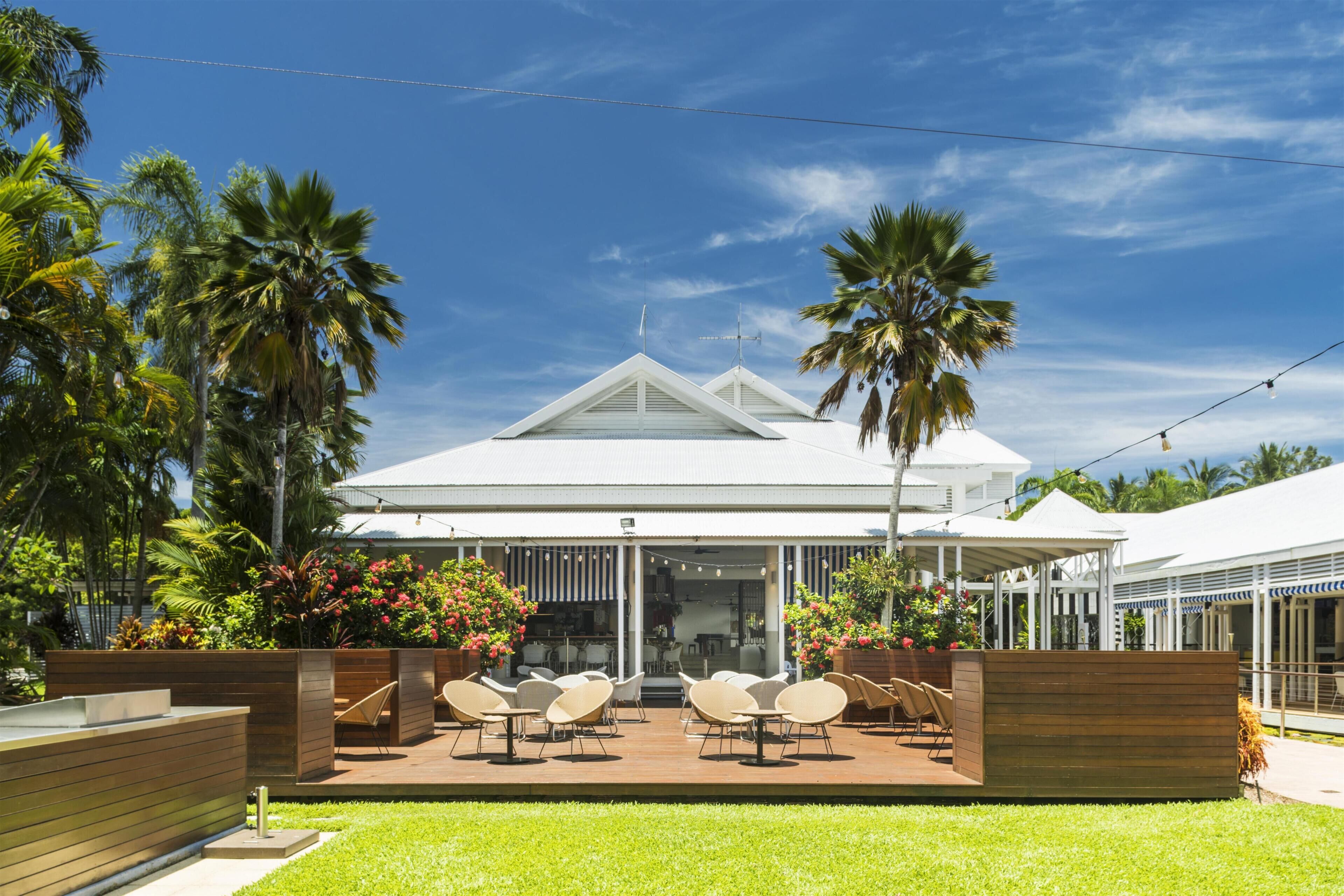 A modern house with a covered patio, outdoor seating, and lush greenery.
