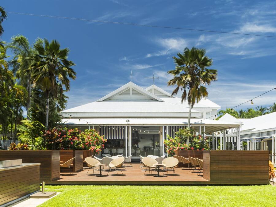A modern house with a covered patio, outdoor seating, and lush greenery.