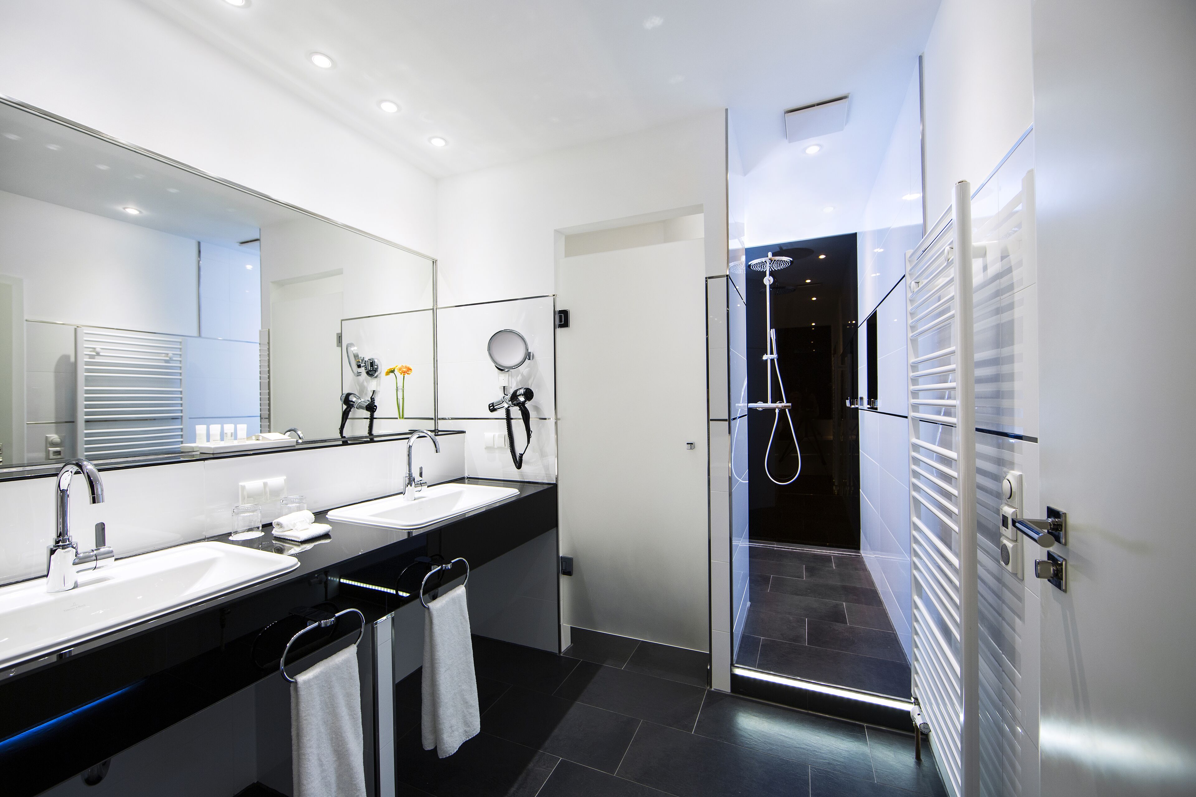 Un baño moderno con lavamanos dobles, un espejo grande y cabina de ducha con paredes de vidrio.