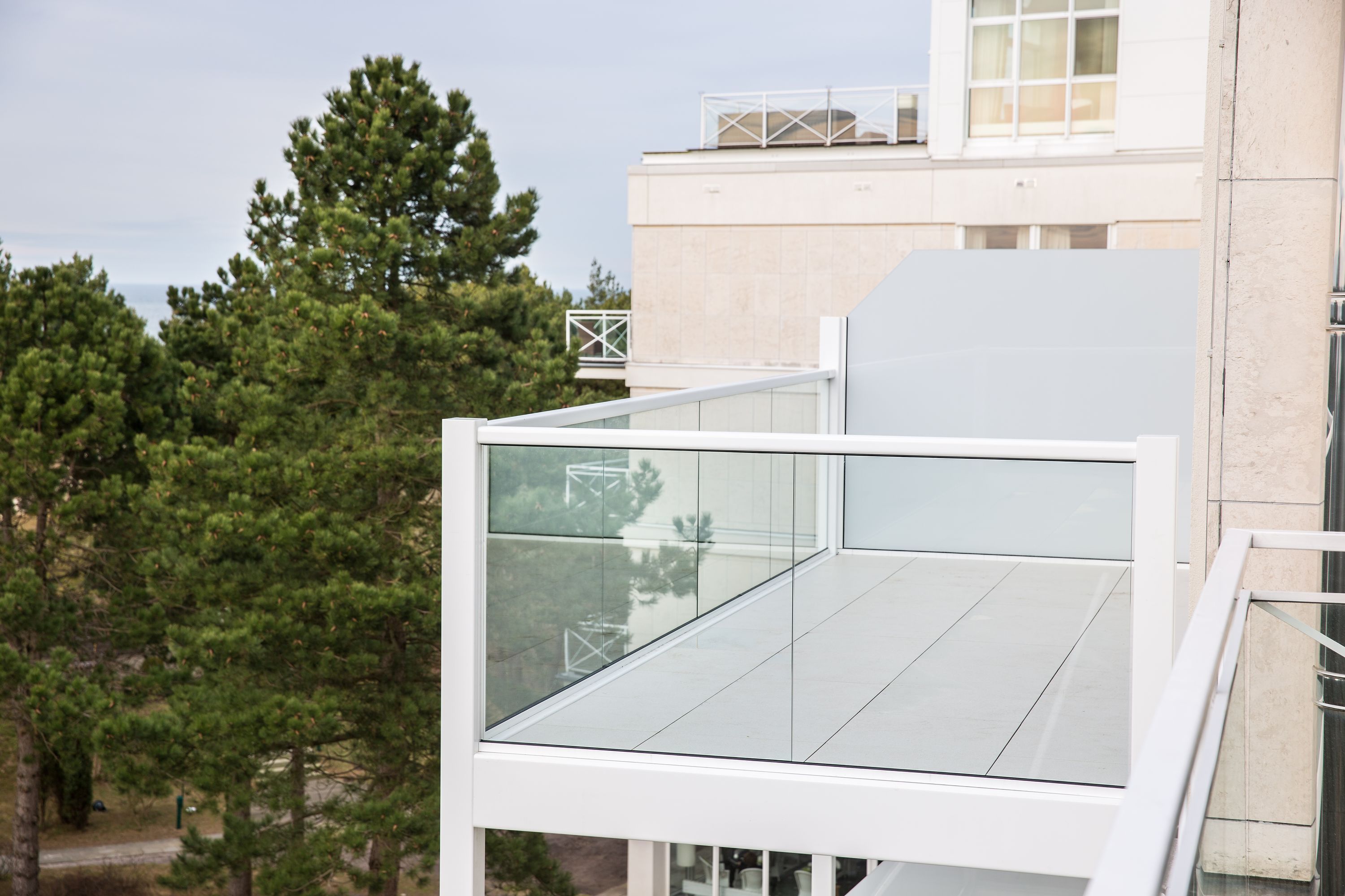 Ein modernes Gebäude mit einem Glasbalkon, umgeben von Bäumen.