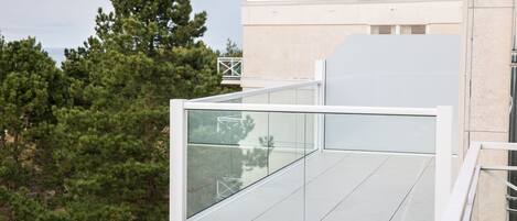 Ein modernes Gebäude mit einem Glasbalkon, umgeben von Bäumen.