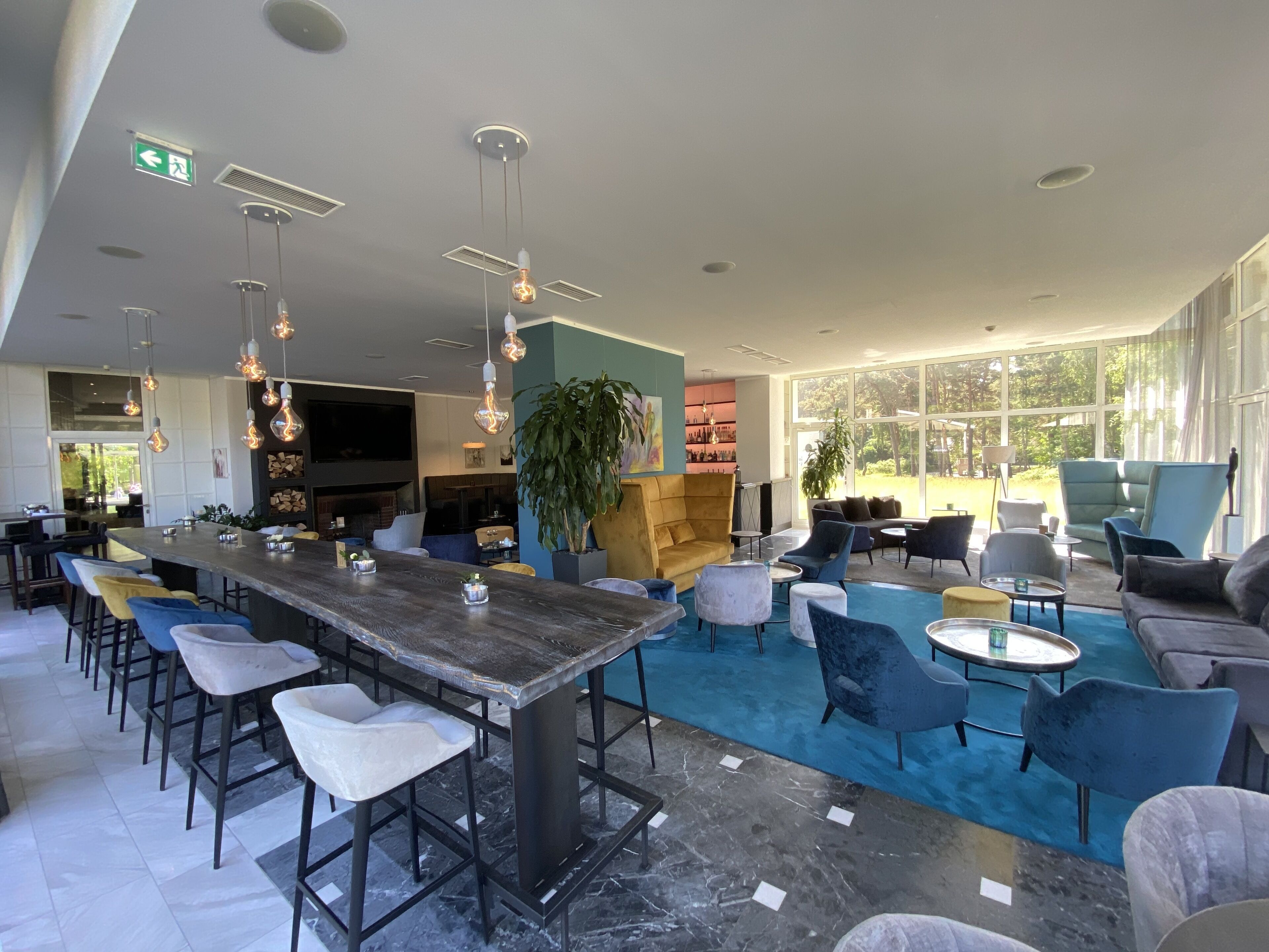 A modern bar area with a long counter, bar stools, and hanging light fixtures.