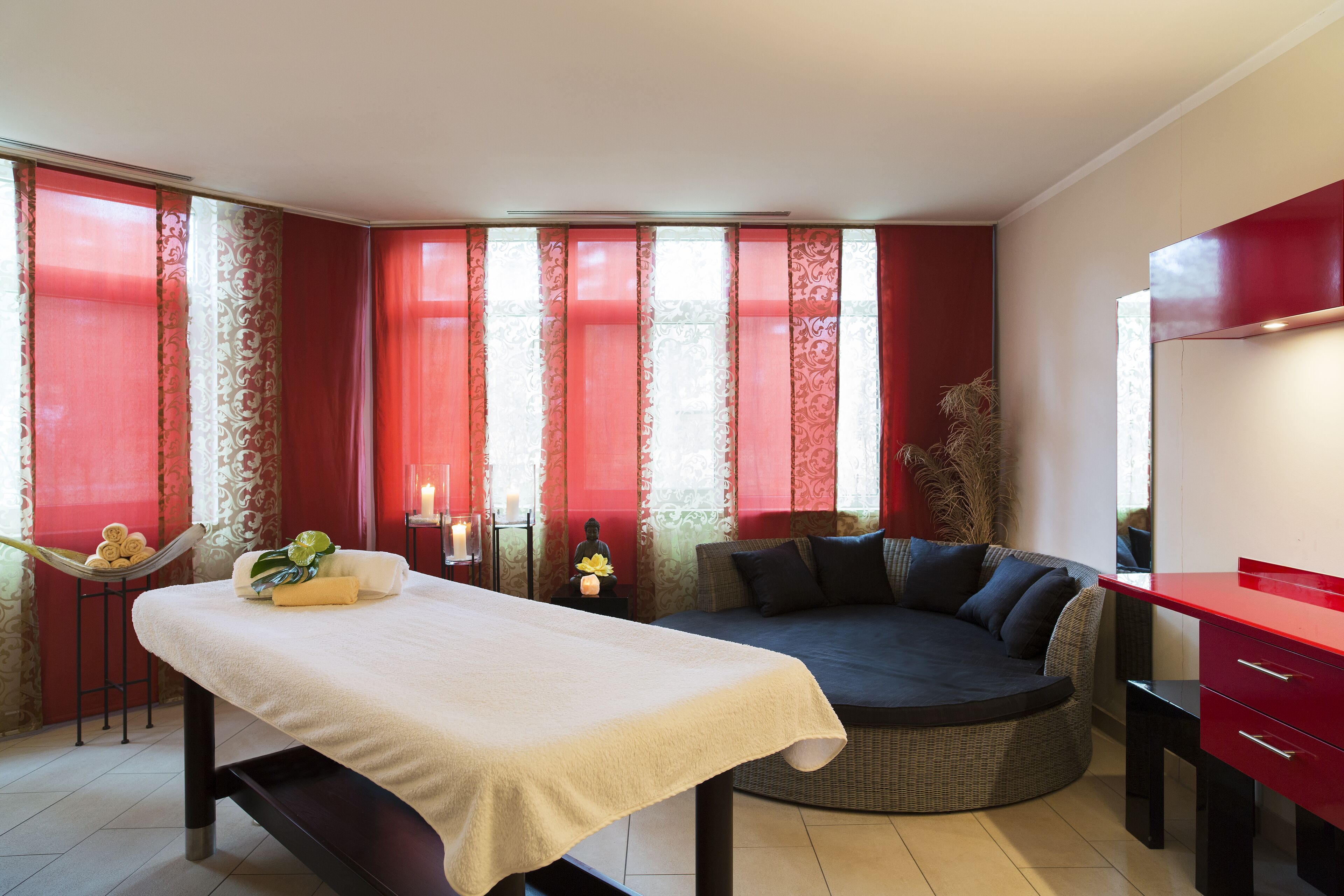Et spa-rum med massagestol, sofa og et rødt skab.