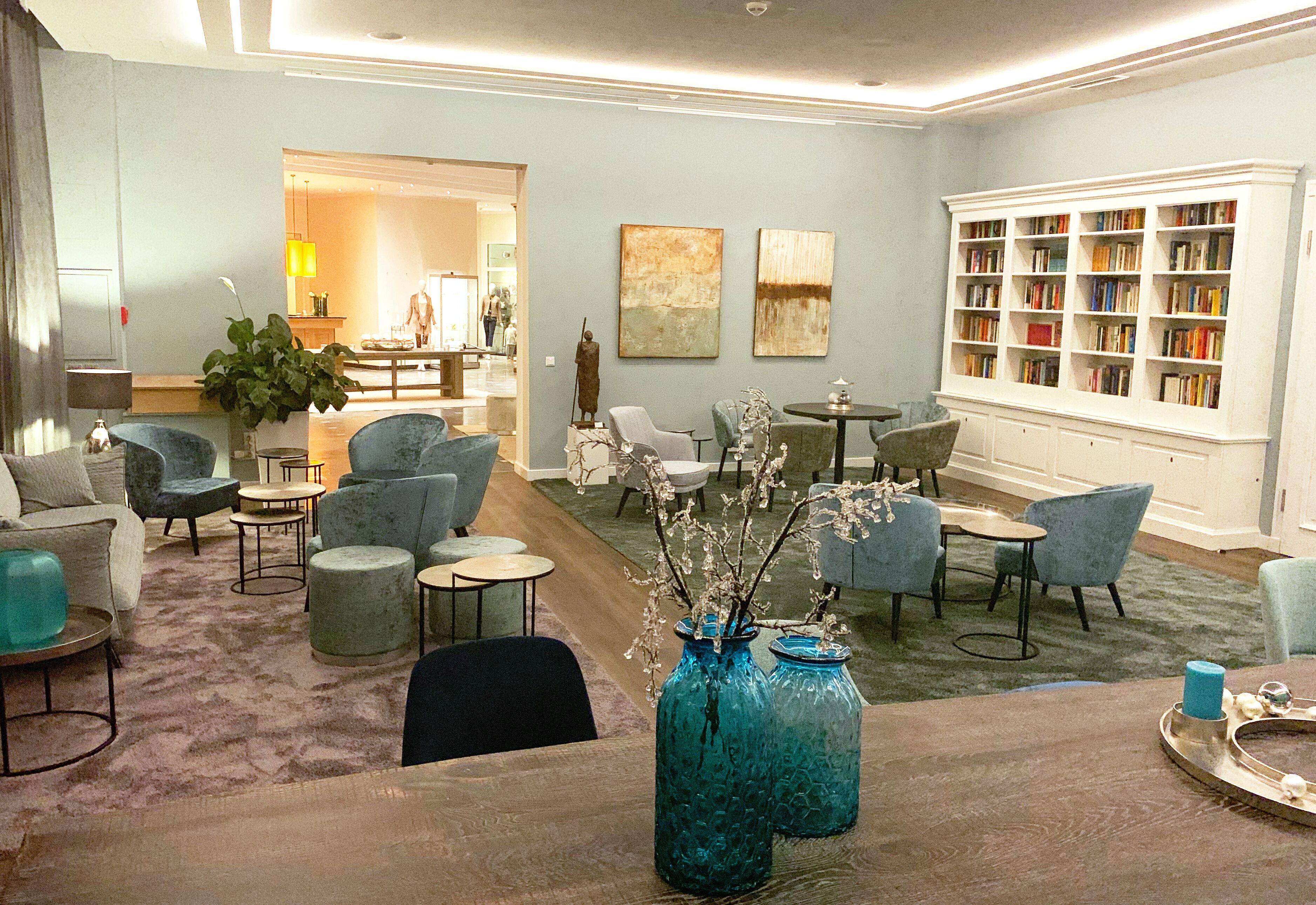 A spacious living area with comfortable seating, a large bookshelf, and decorative vases.