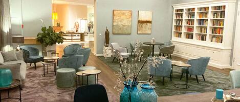 A spacious living area with comfortable seating, a large bookshelf, and decorative vases.