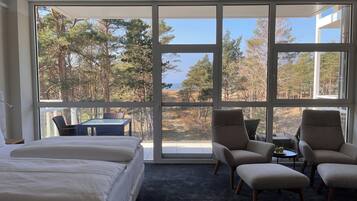 A bedroom with a large window, a bed, and two armchairs.