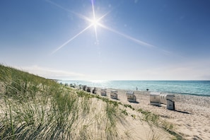 Une plage avec des dunes de sable et des cabanes de plage.