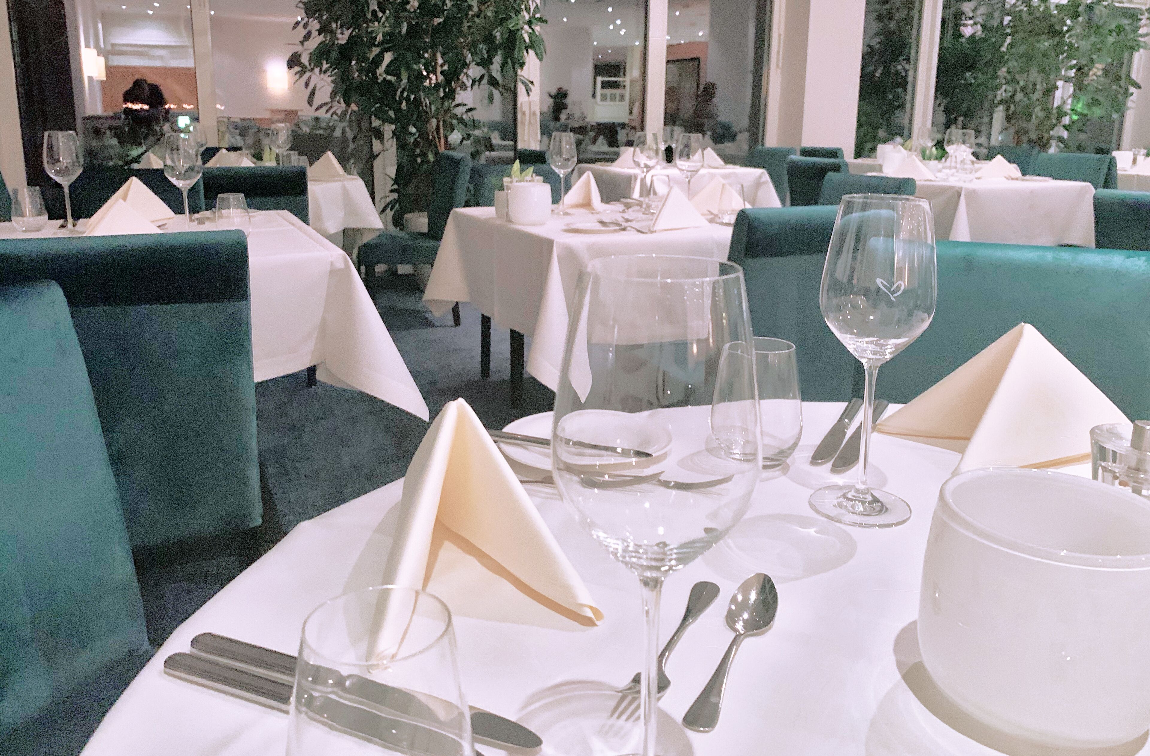 Ein Restaurant mit gedeckten Tischen, einschließlich Tellern, Gläsern und Besteck.