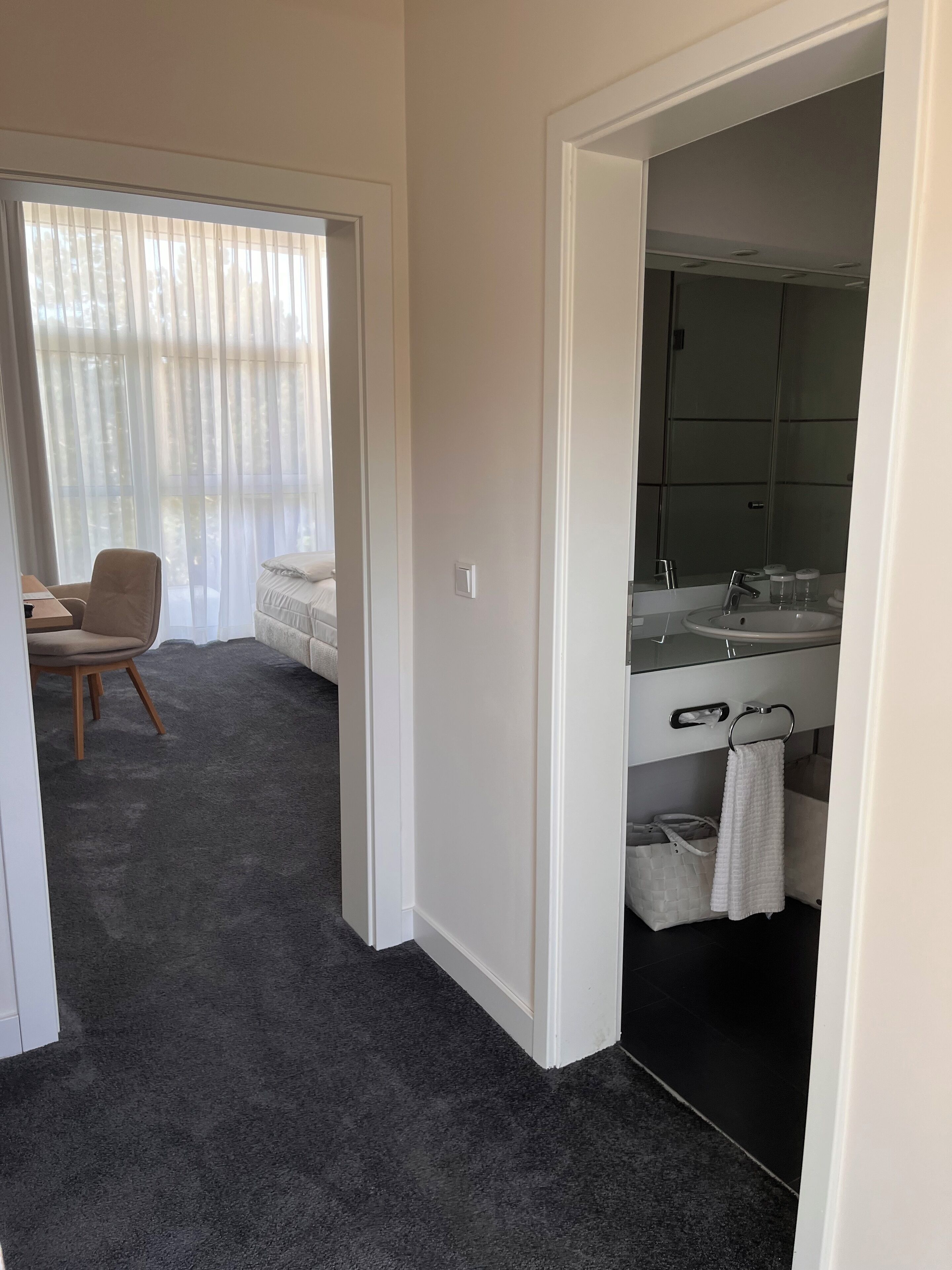 A modern bathroom with a large mirror, a sink, and a towel rack.