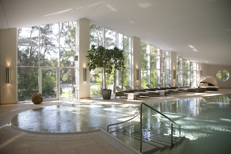Una piscina techada, sillones reclinables de piscina. Strandhotel Fischland
