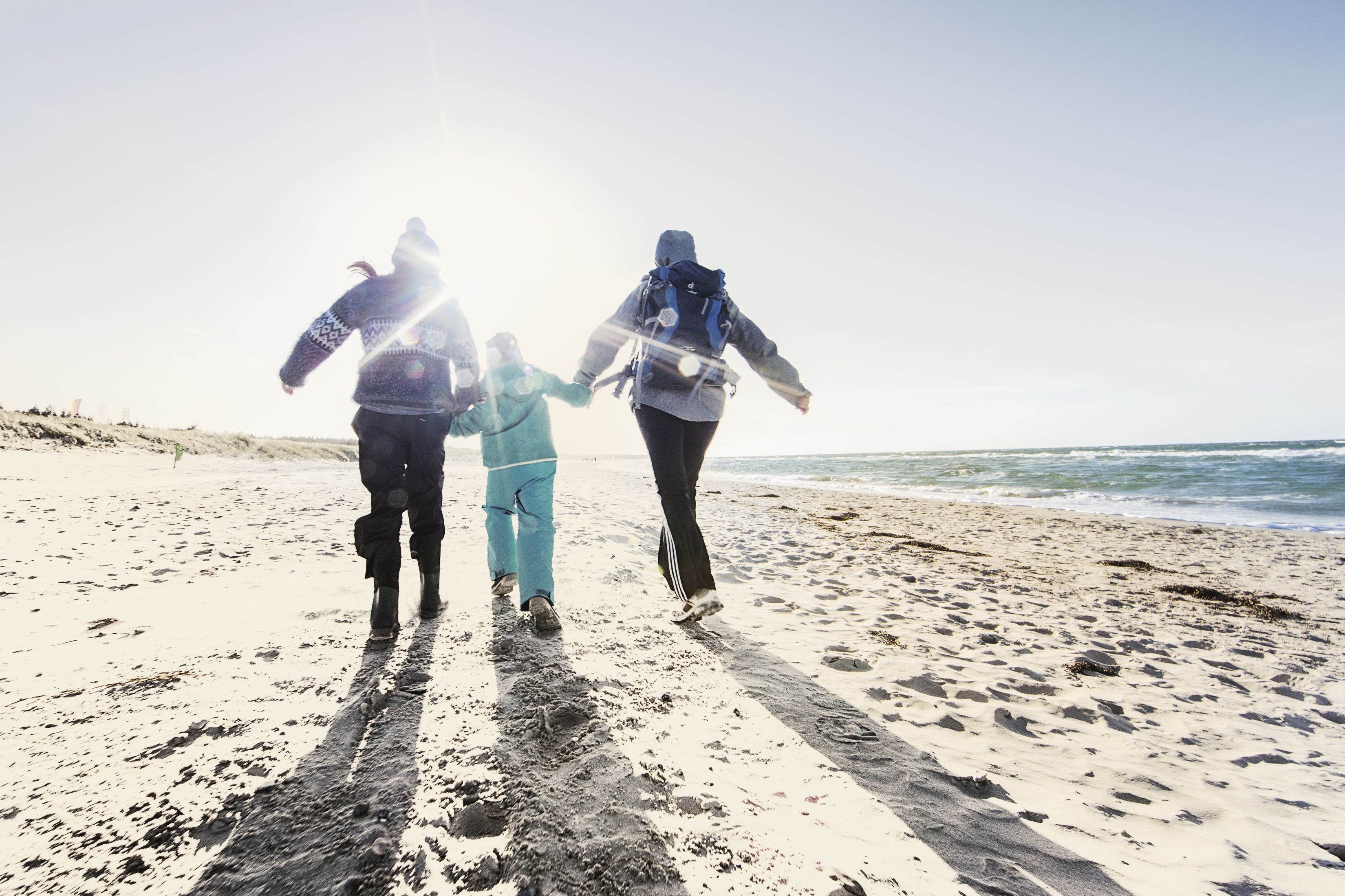 A family walking on a sandy beach with the ocean in the background.