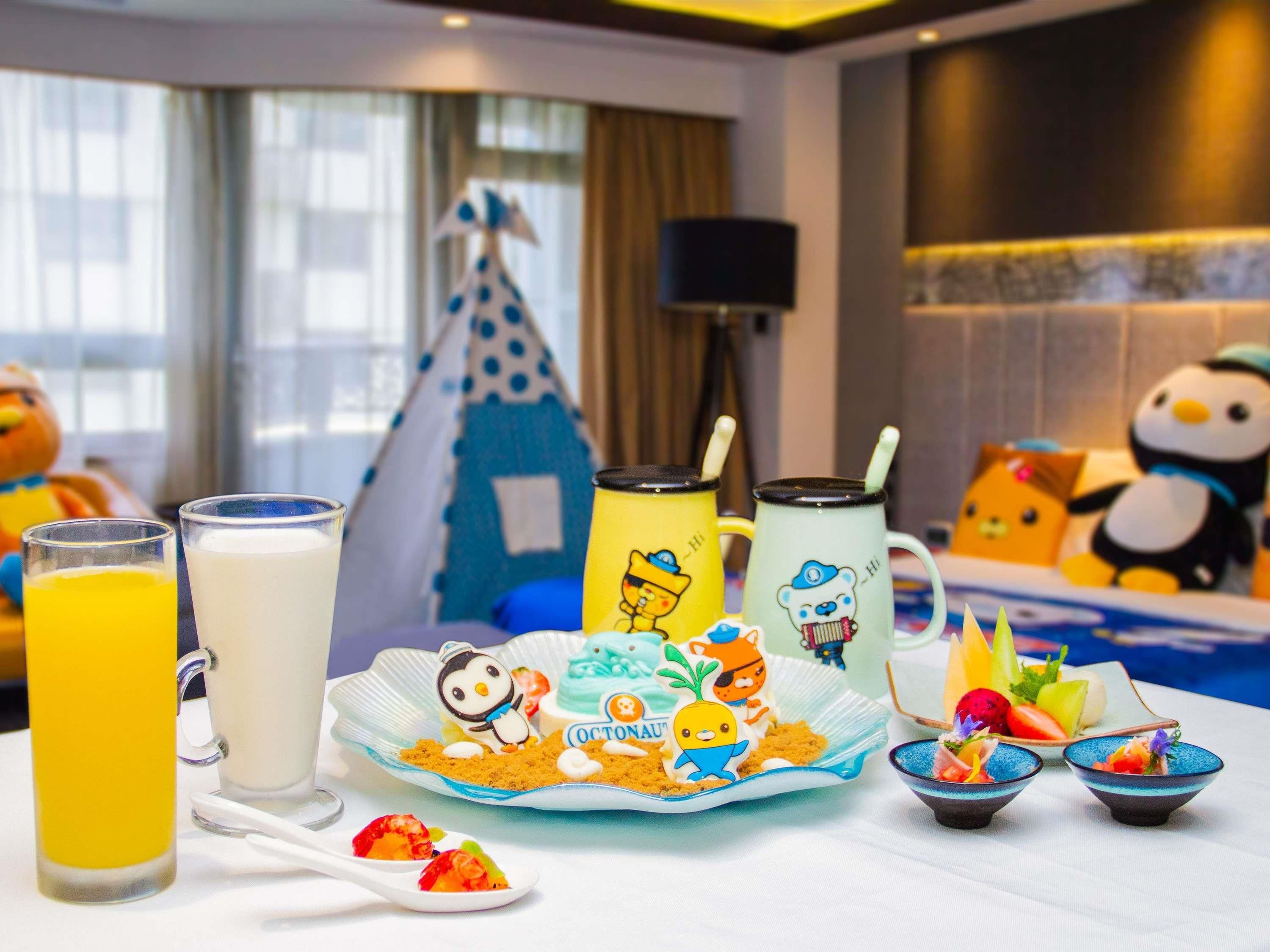 A breakfast setup with drinks, a plate of food, and a decorative penguin figure.