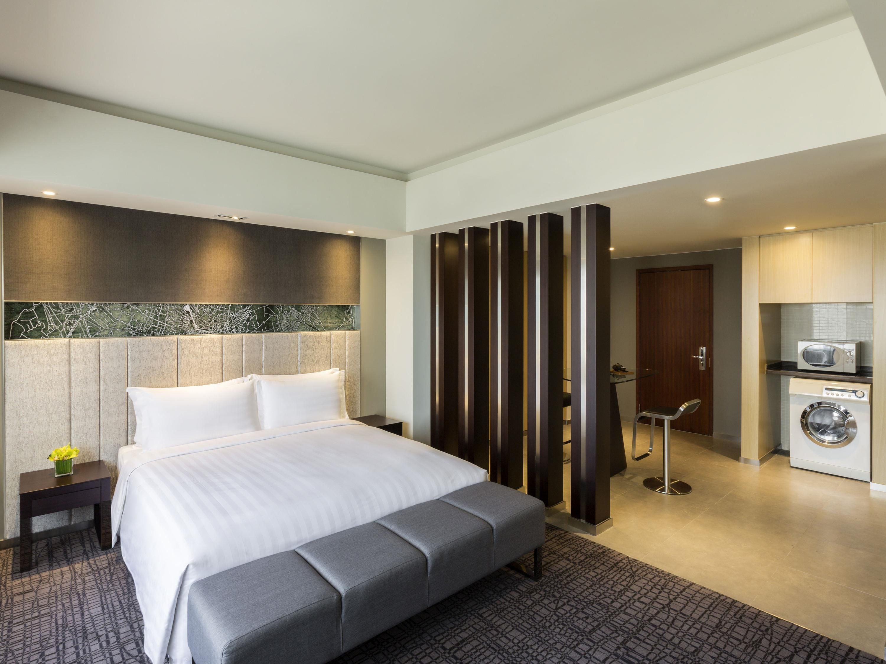 Ein modernes Hotelzimmer mit einem großen Bett, einer separaten Sitzecke, einer Küchenzeile und einem Badezimmer.