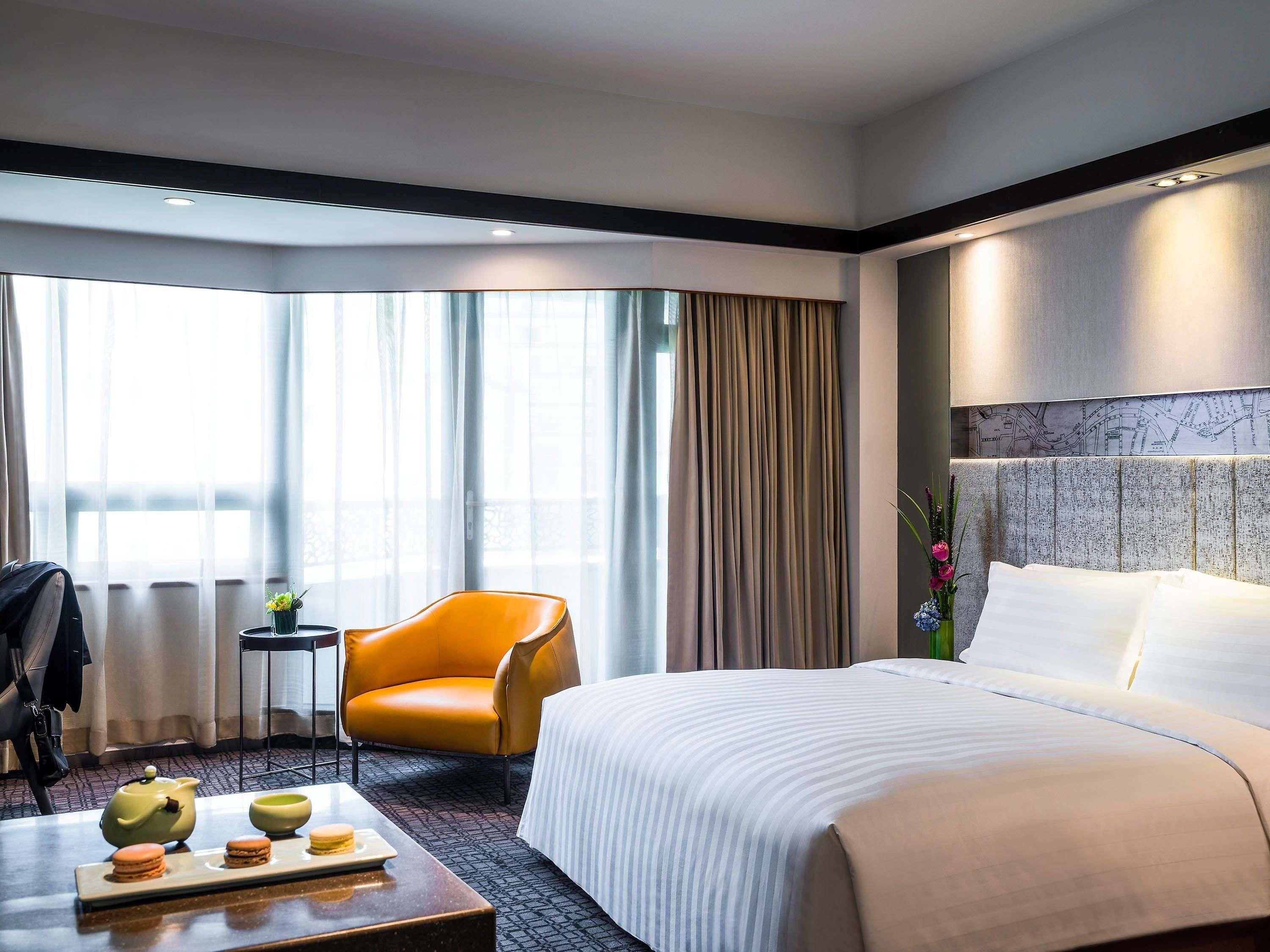 A hotel room with a large bed, a seating area with a table, and a window with curtains.