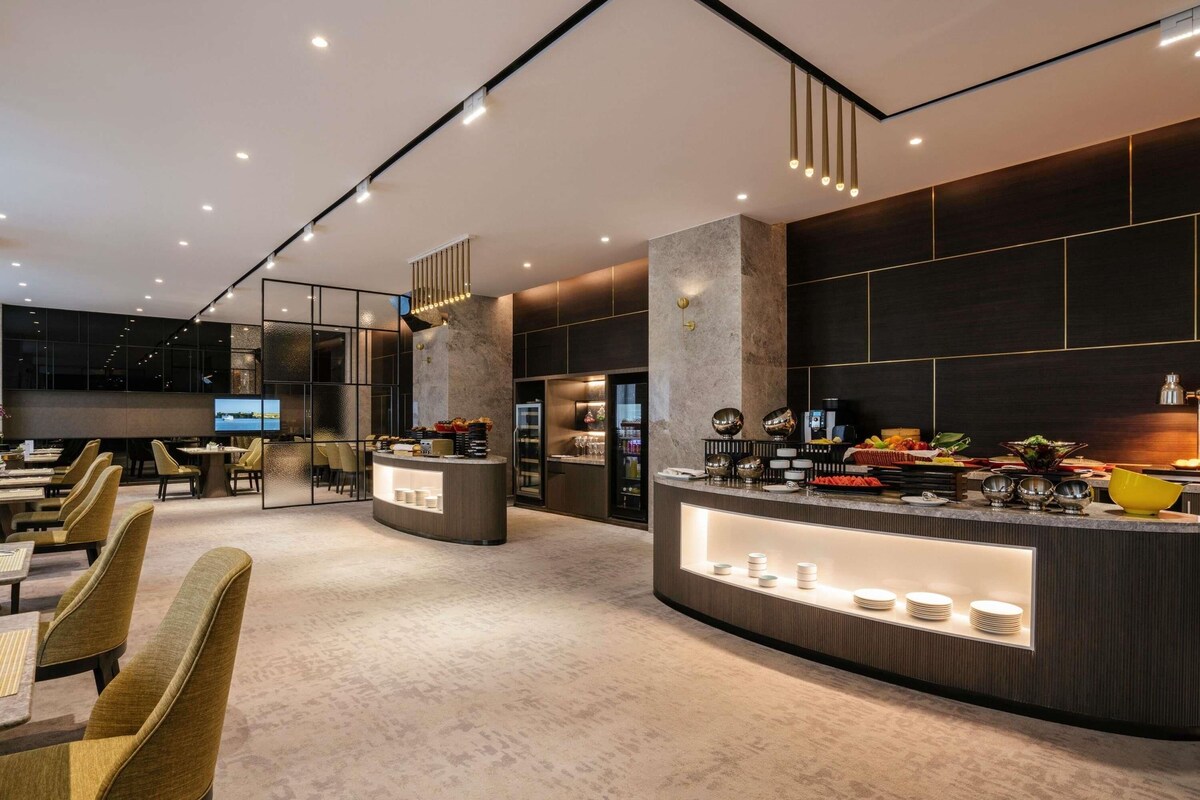 Eine moderne Hotelhalle mit einer zentralen Rezeption, einer Sitzecke und einem großen Fernseher.