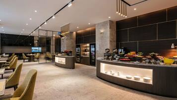 Eine moderne Hotelhalle mit einer zentralen Rezeption, einer Sitzecke und einem großen Fernseher.