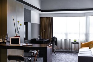 A modern hotel room with a desk, chair, and a bed.