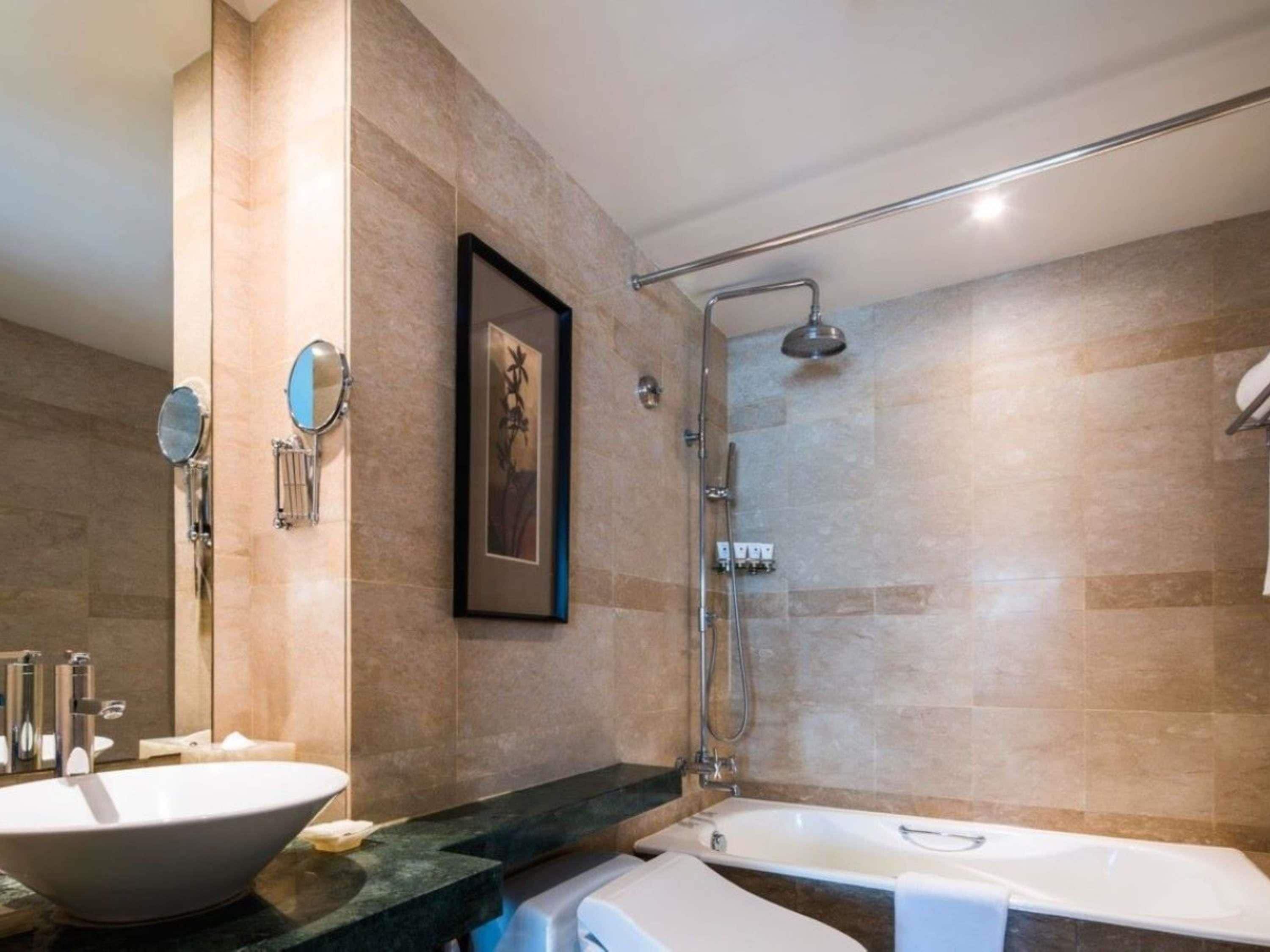 A modern bathroom with a large bathtub, a separate shower area, and a vanity with a bowl sink.