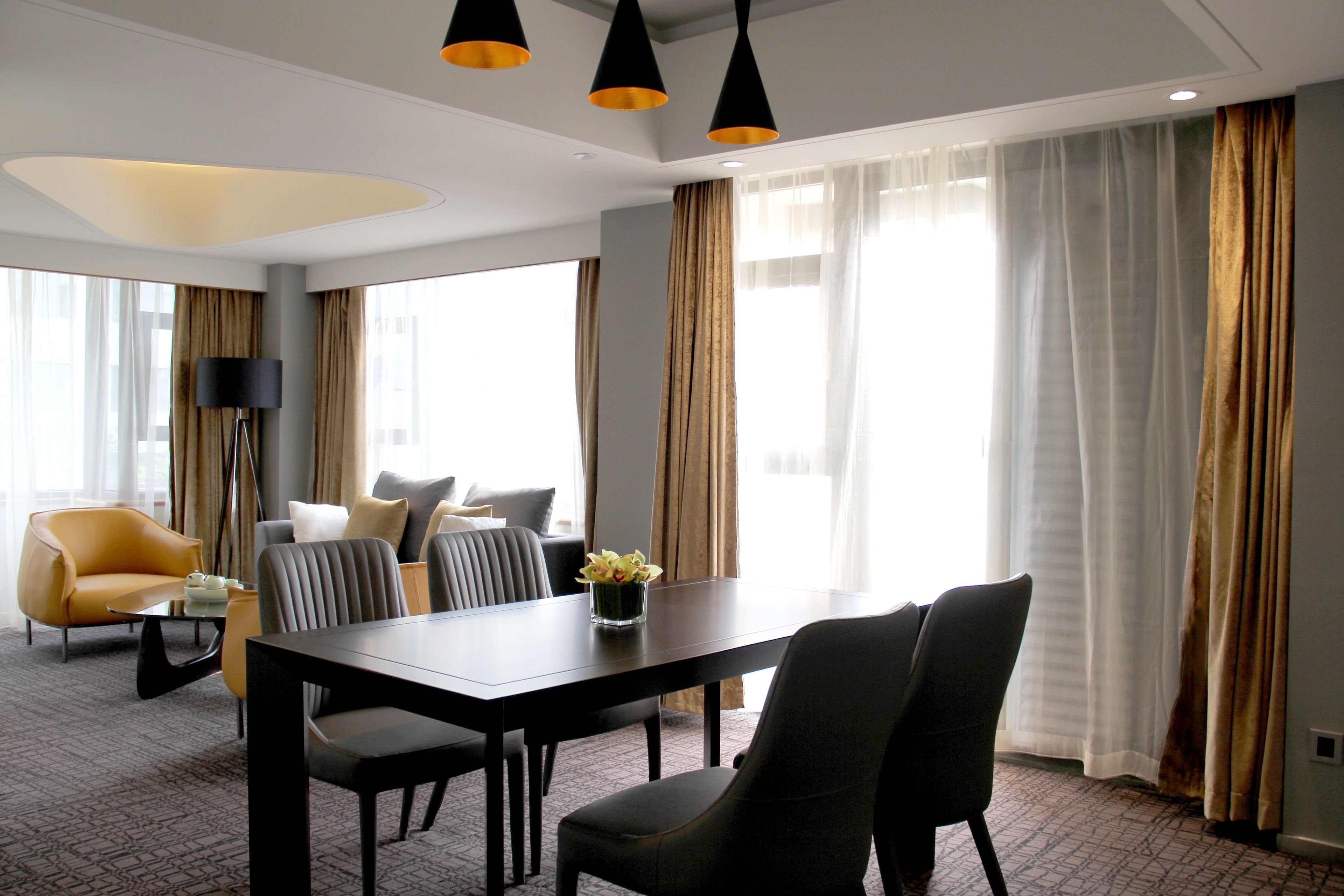 Ein modernes Hotelzimmer mit Essbereich, einer Couch und einer Lampe.