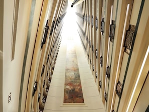 Un couloir orné d’une œuvre d’art centrale, flanqué de panneaux muraux symétriques et d’éléments décoratifs noirs.