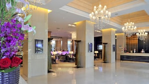 A spacious lobby with chandeliers, a reception desk, and a seating area.