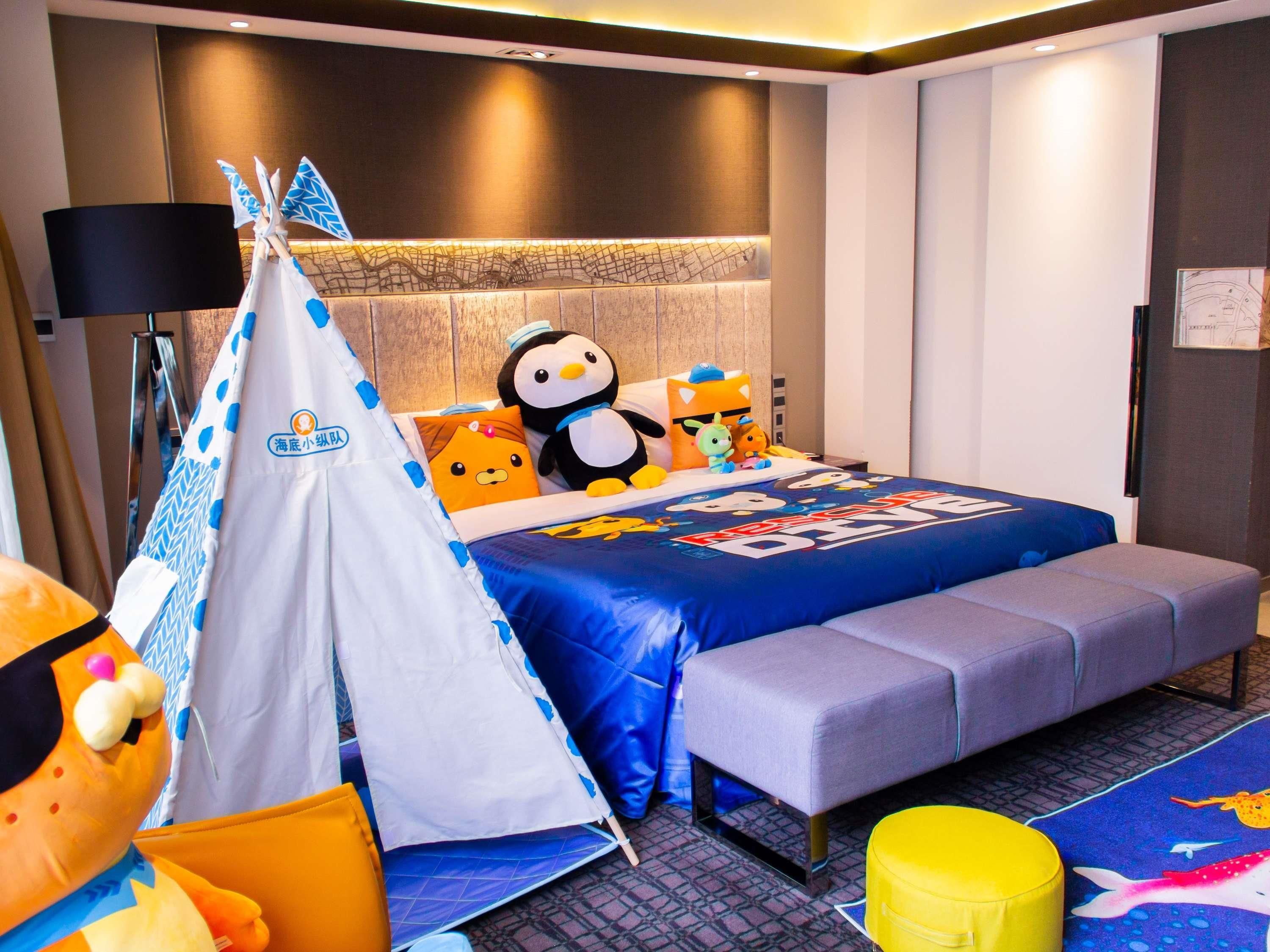Une chambre d’hôtel avec un lit, une tente et des peluches.