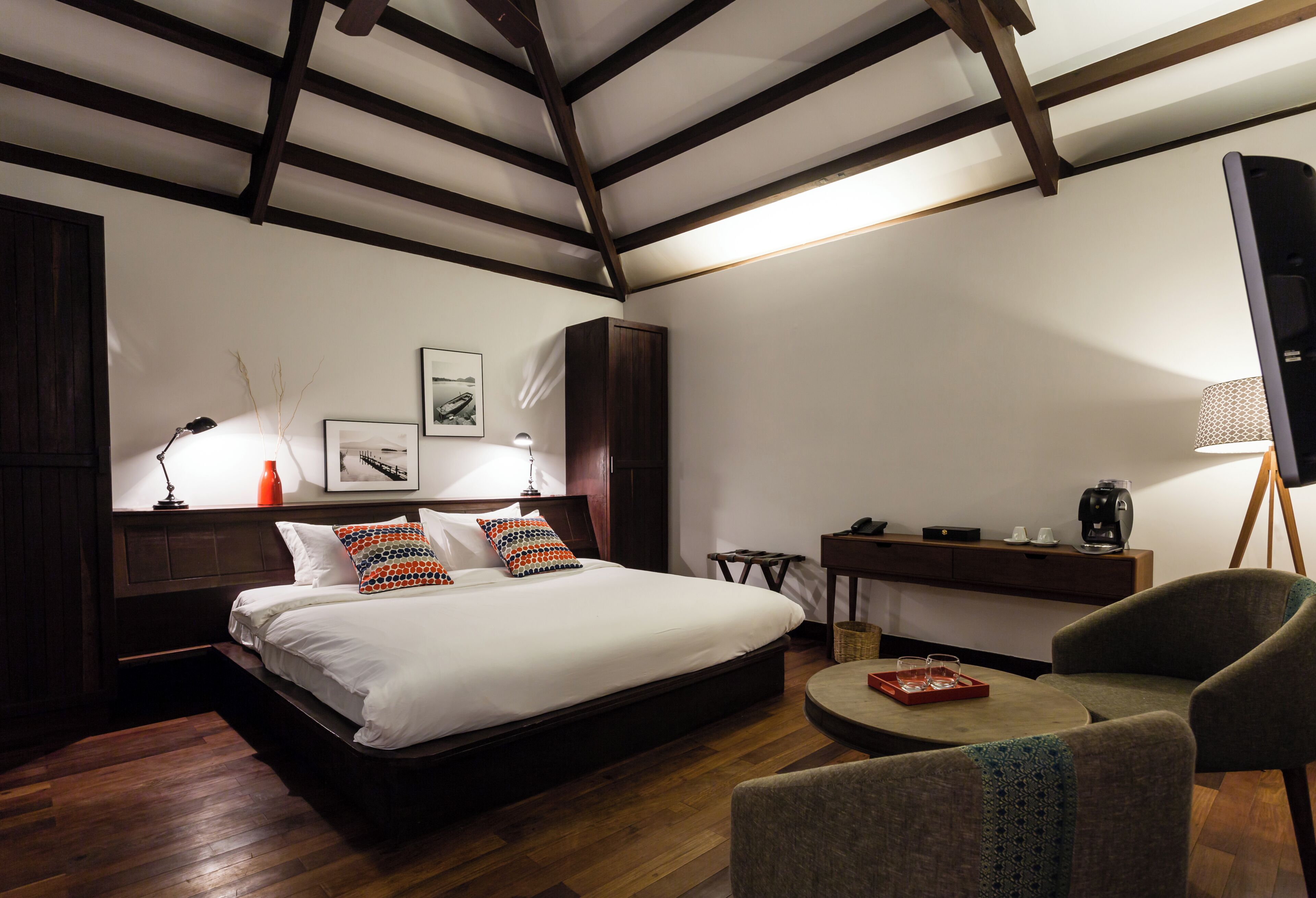 Un dormitorio con una cama, mesitas de noche, un escritorio, una silla y una lámpara.