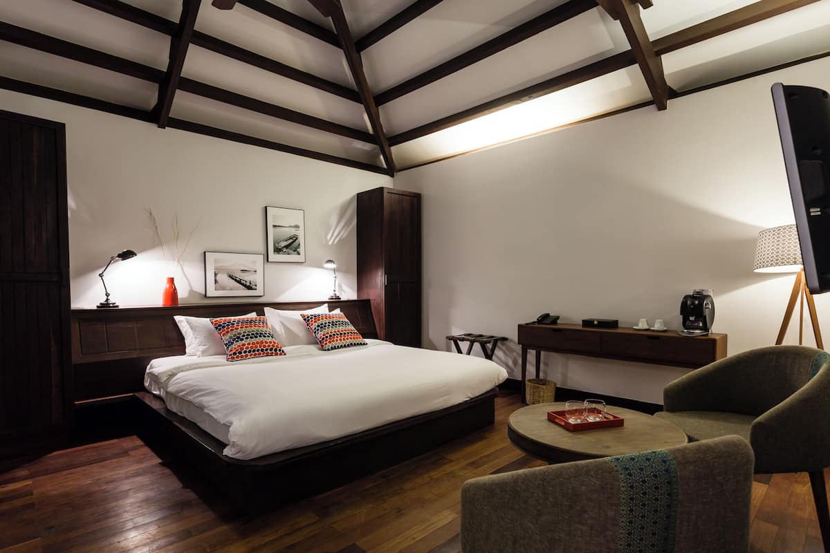 Un dormitorio con una cama, mesitas de noche, un escritorio, una silla y una lámpara.
