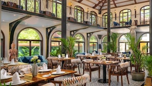 Een ruim restaurant met hoge plafonds, gebogen ramen en meerdere eetgedeeltes.