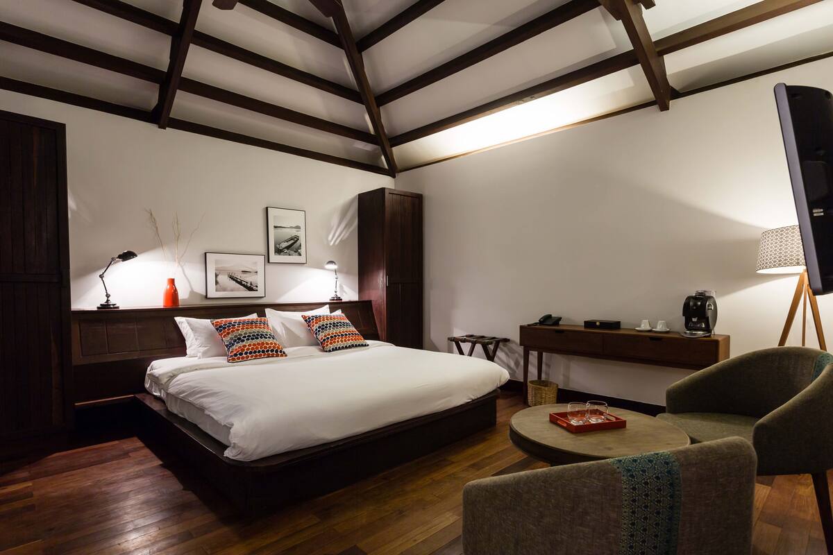 Een slaapkamer met een groot bed, een bureau, een stoel en een televisie.