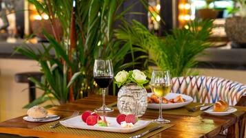 A table set with a plate of food, two glasses of wine, and a decorative vase.