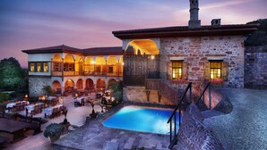 A courtyard with a pool, outdoor seating, and a stone building with arches and a staircase. - Heritage Homes Mehmet Ali Aga Konagi (Datça)