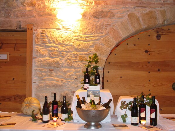 Una mesa con botellas de vino y un bol de hielo, frente a una pared de piedra con vigas de madera.