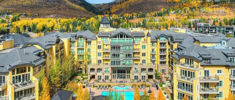 A hotel with multiple floors, a central courtyard with a pool, and a mountainous backdrop.