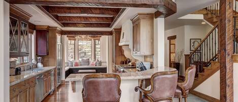 Una cocina amplia con vigas de madera, una isla central y taburetes de bar.